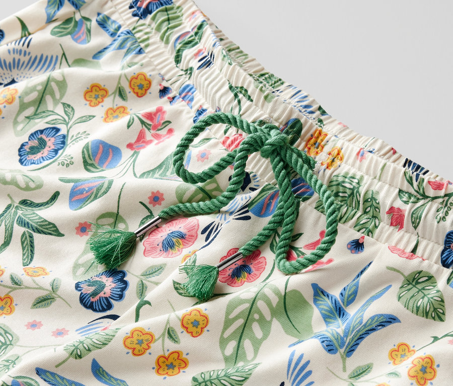Detail pyžamových kalhot s květinovým vzorem a zelenou šňůrkou v pase.