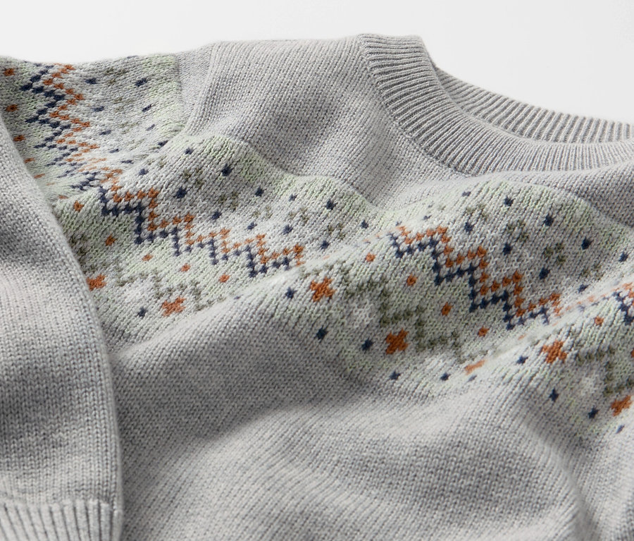 Detail dětského pleteného svetru se vzorem.