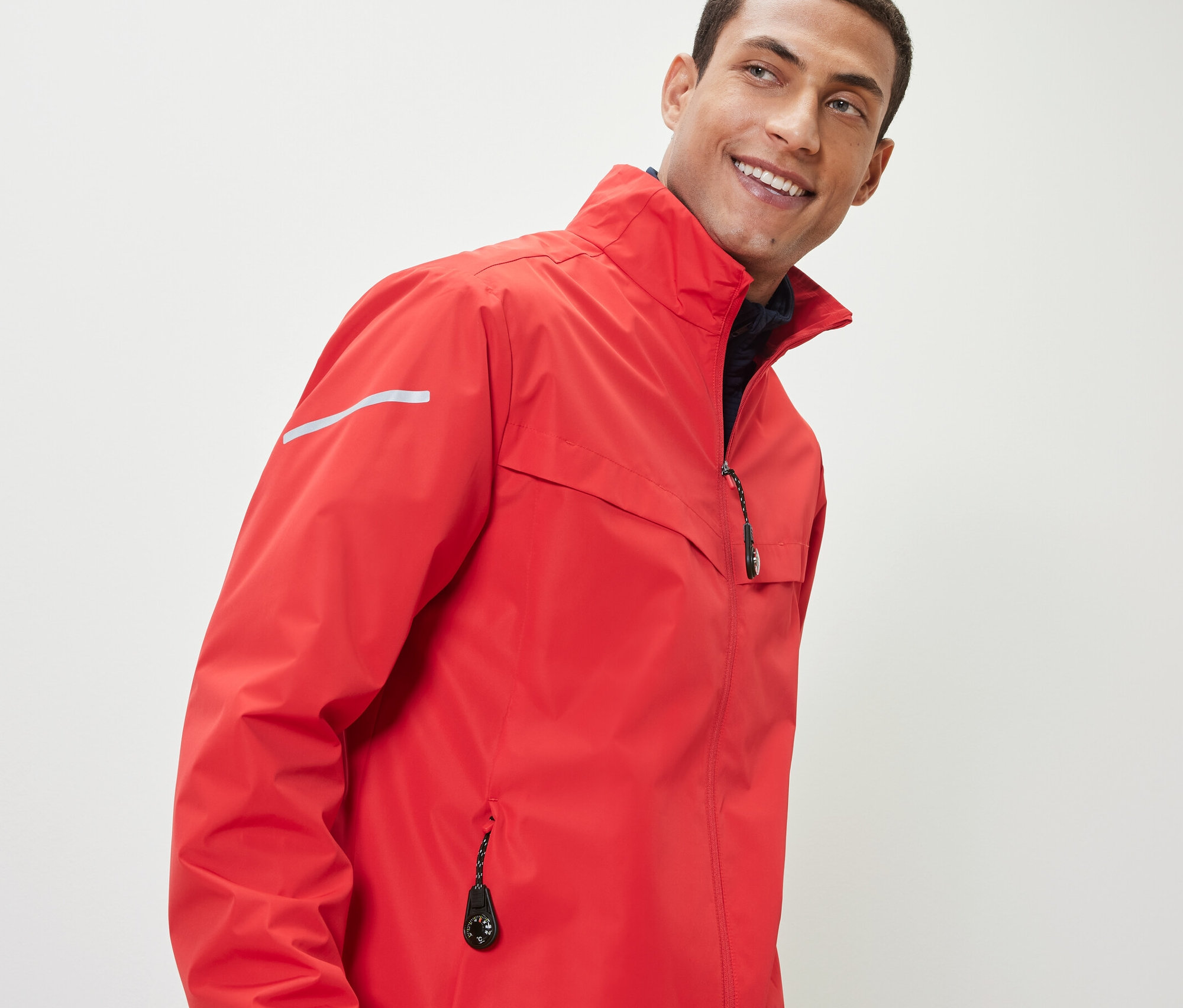 Muž v červené bundě s 2 přívěsky na zip.