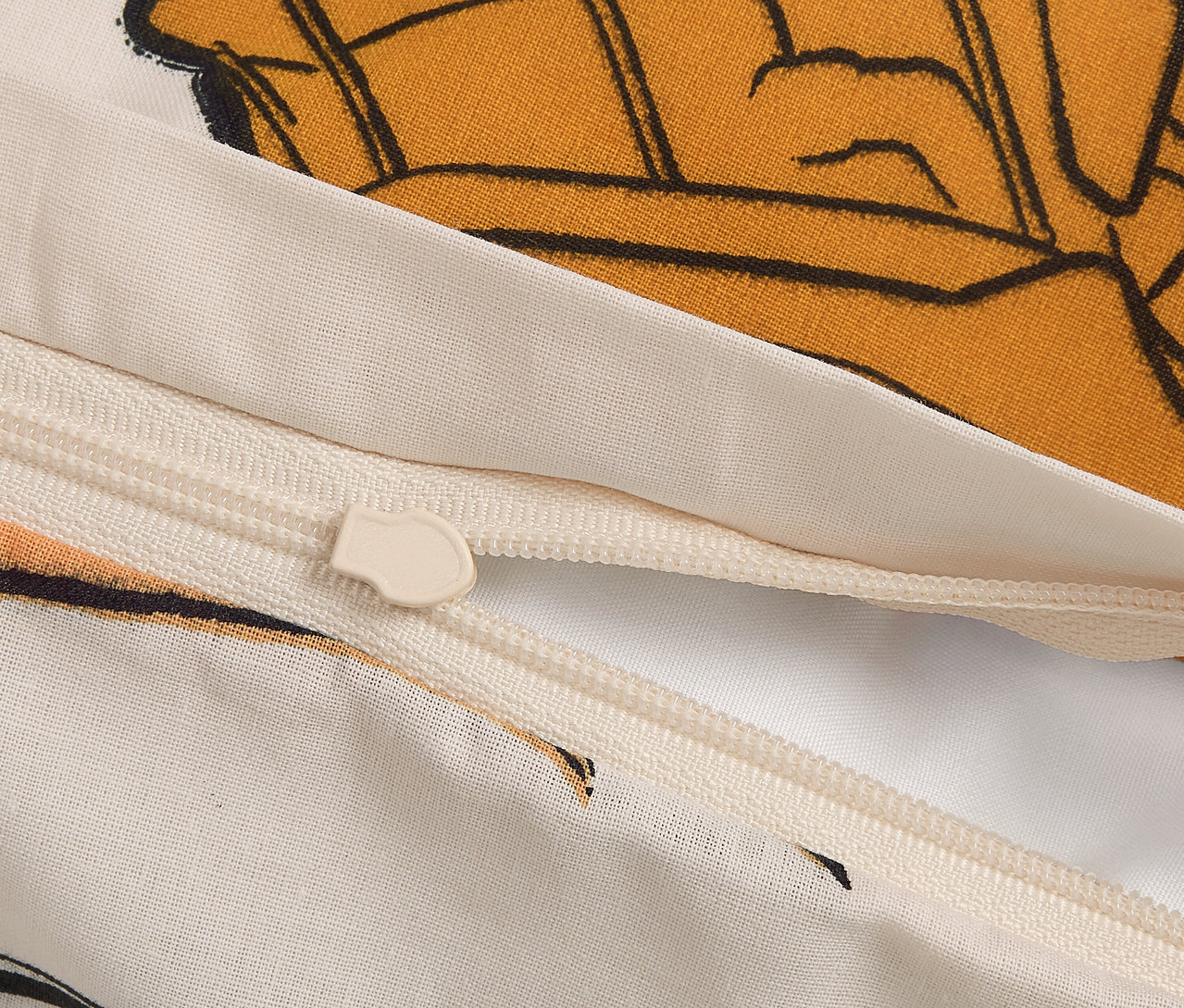 Detail zipu na povlečení s kresleným motivem.