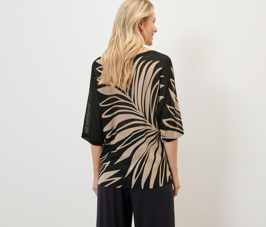 Žena má na sobě svetr z jemného úpletu s potiskem.