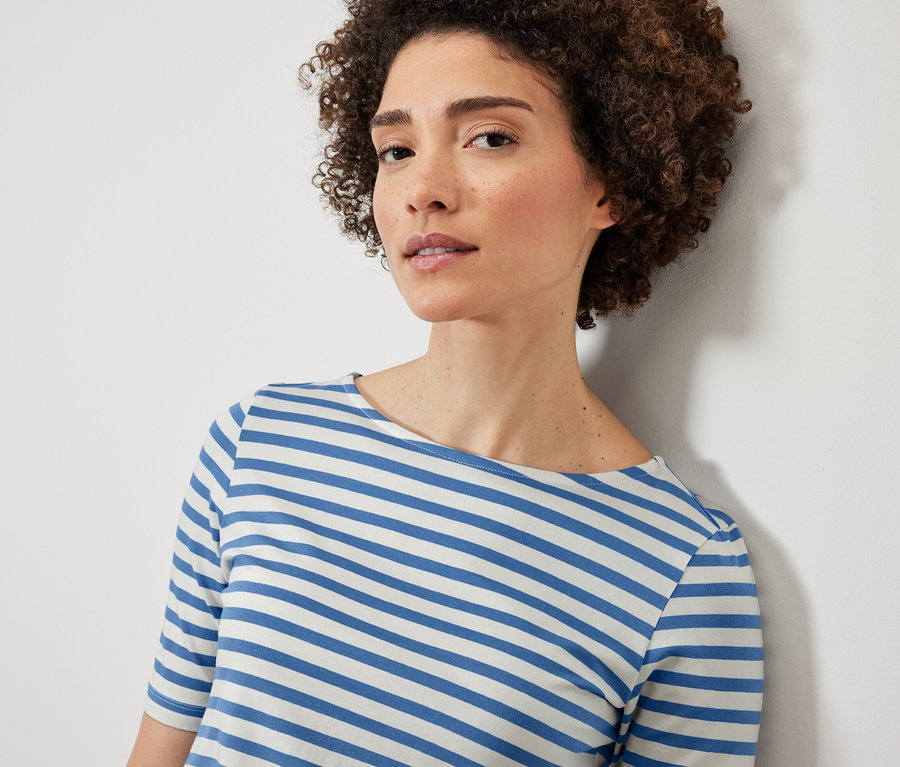 Žena má na sobě modrobílé pruhované tričko s polodlouhým rukávem.