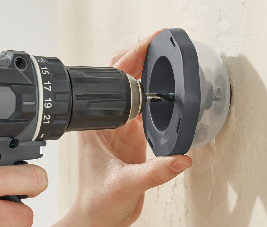 Osoba vrtá vrtačkou skrz lapač prachu Bohrstaubfänger do zdi.