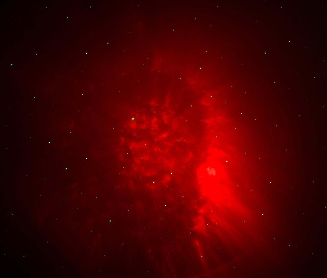 Červená mlhovina s hvězdami na tmavém pozadí.