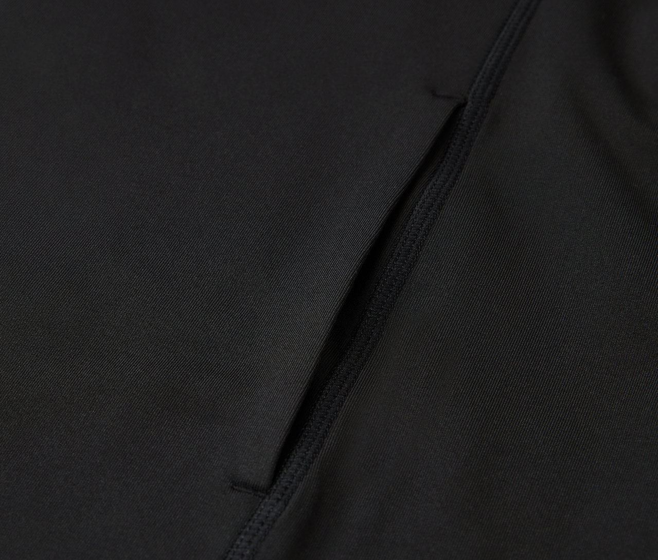 Detail černého sportovního oblečení s kapsou.