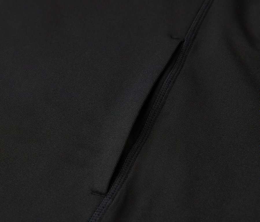 Detail černého sportovního oblečení s kapsou.