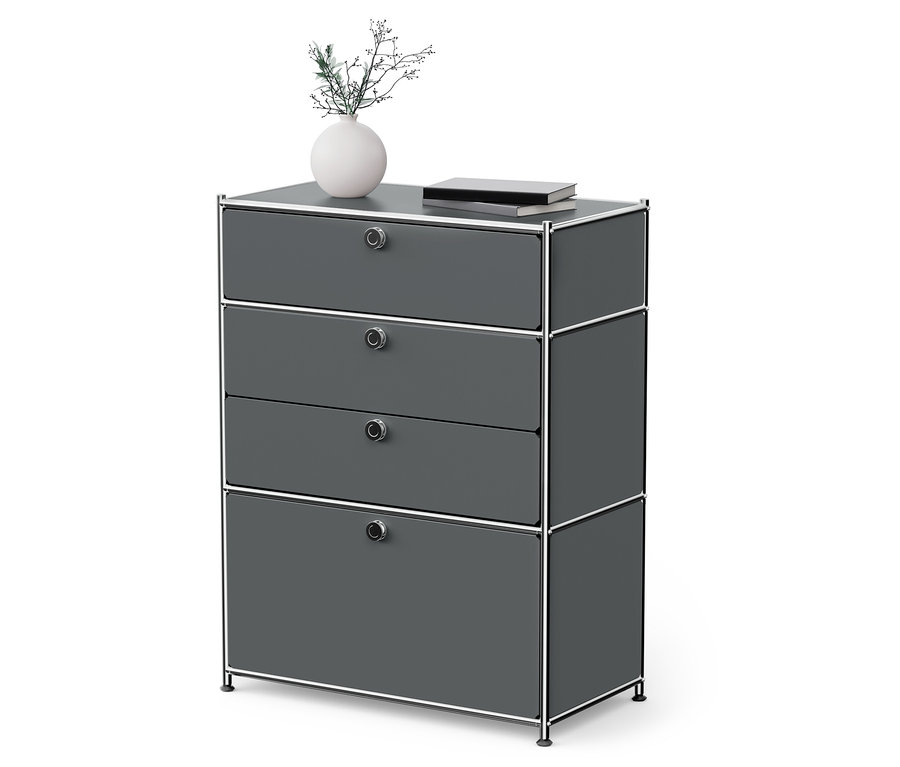 Čtyřzásuvková komoda šedé barvy s chromovaným rámem. Na komodě je váza s květinami a kniha.