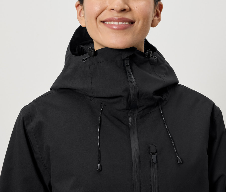 Usmívající se žena má na sobě černou bundu s kapucí.