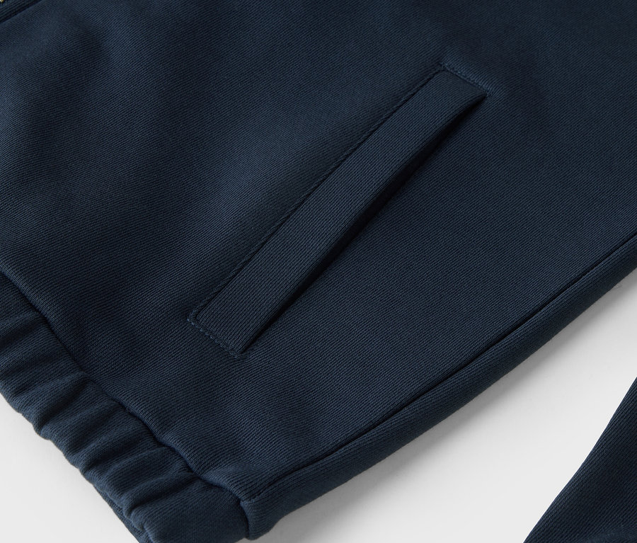 Detailní záběr na tmavě modrou mikinu na zip s kapsou.