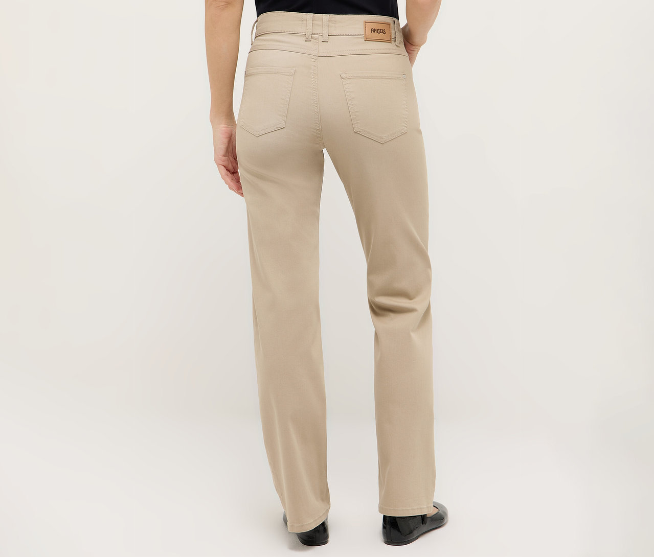 Pohled zezadu na ženu v béžových kalhotách a černých botách.