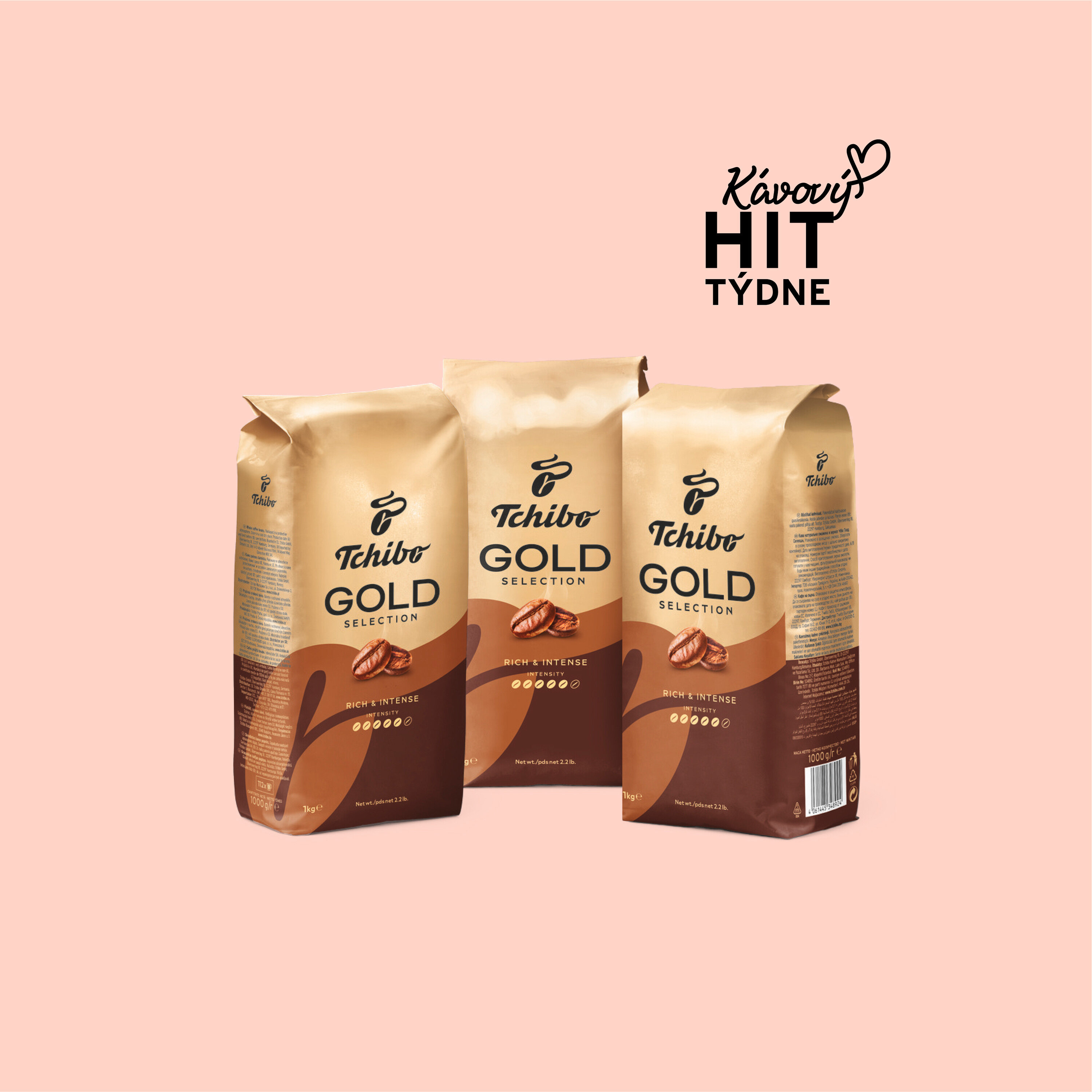 Tři balení kávy Tchibo Gold Selection na světle růžovém pozadí.