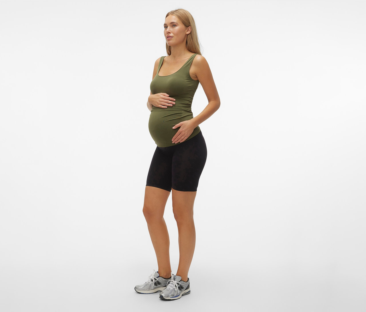 Těhotná žena v olivovém tílku a černých skinny šortkách MAMALICIOUS »MLTIA JEANNE«, mellow buff, stojí bokem.