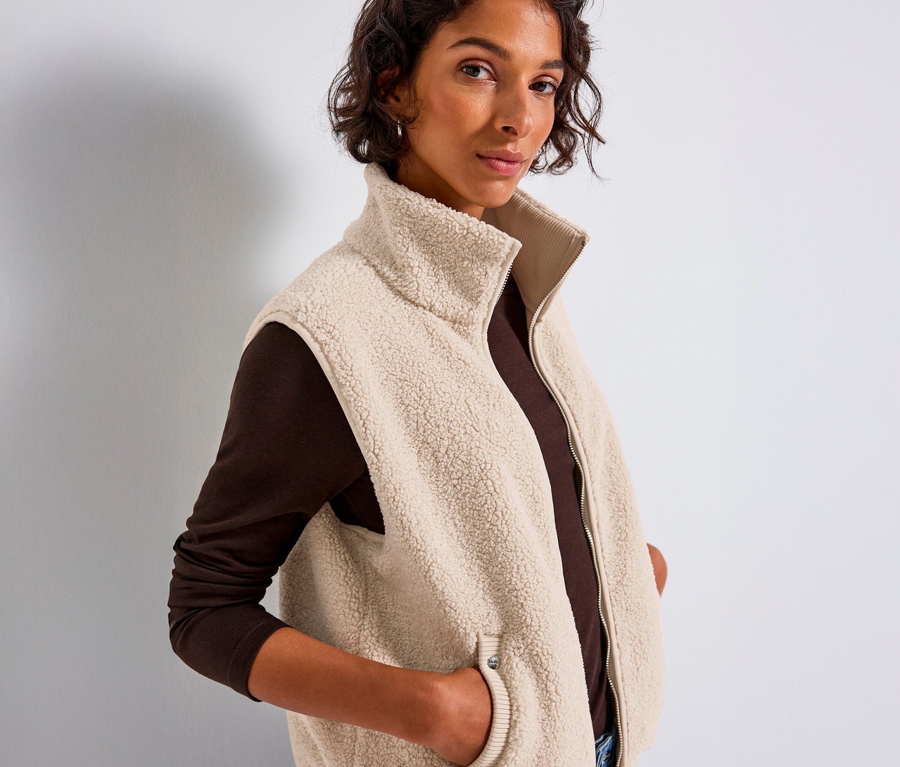 Žena v plyšové vestě Street One má ruce v kapsách.