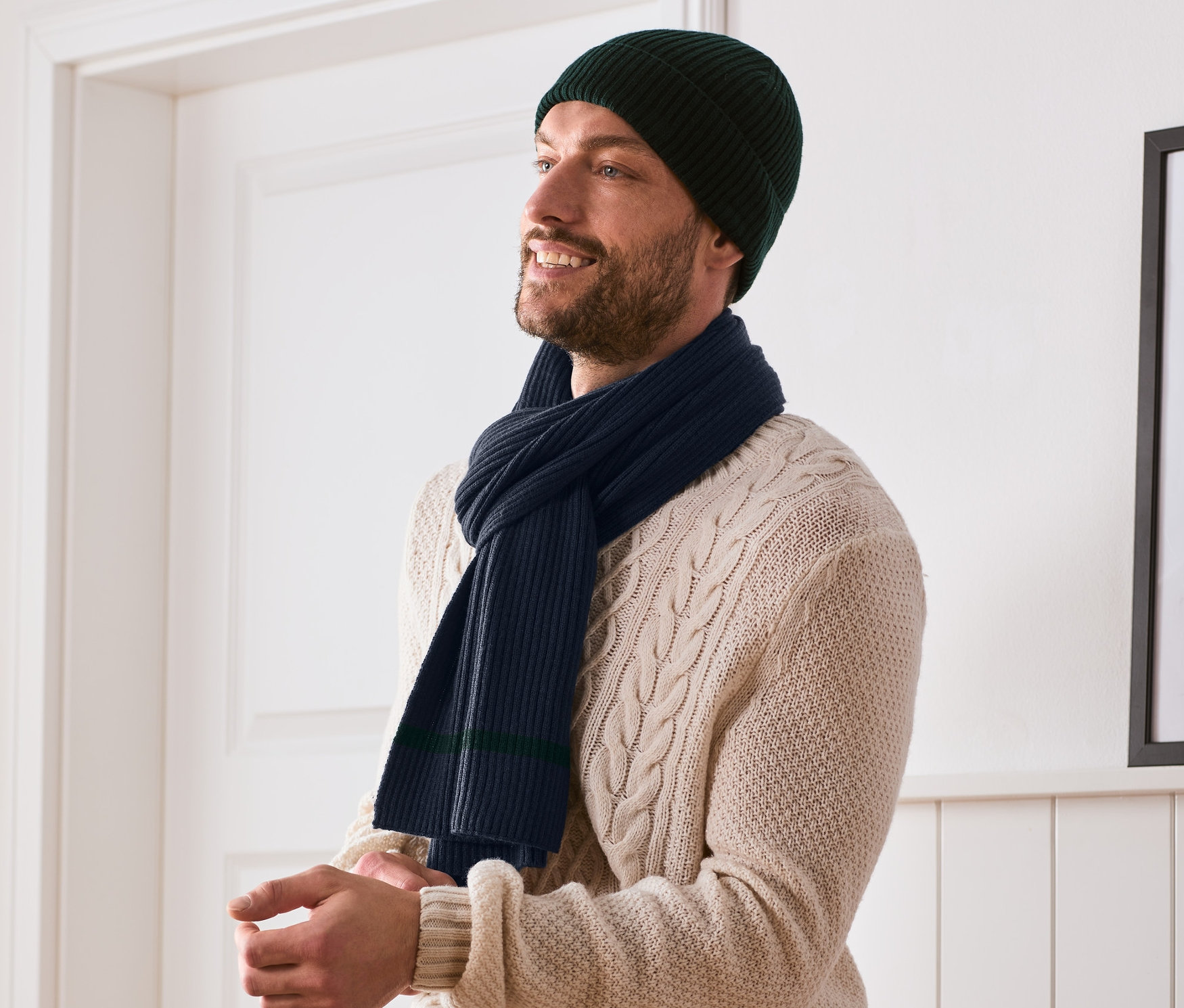 Muž s tmavě zelenou čepicí a pletenou šálou.