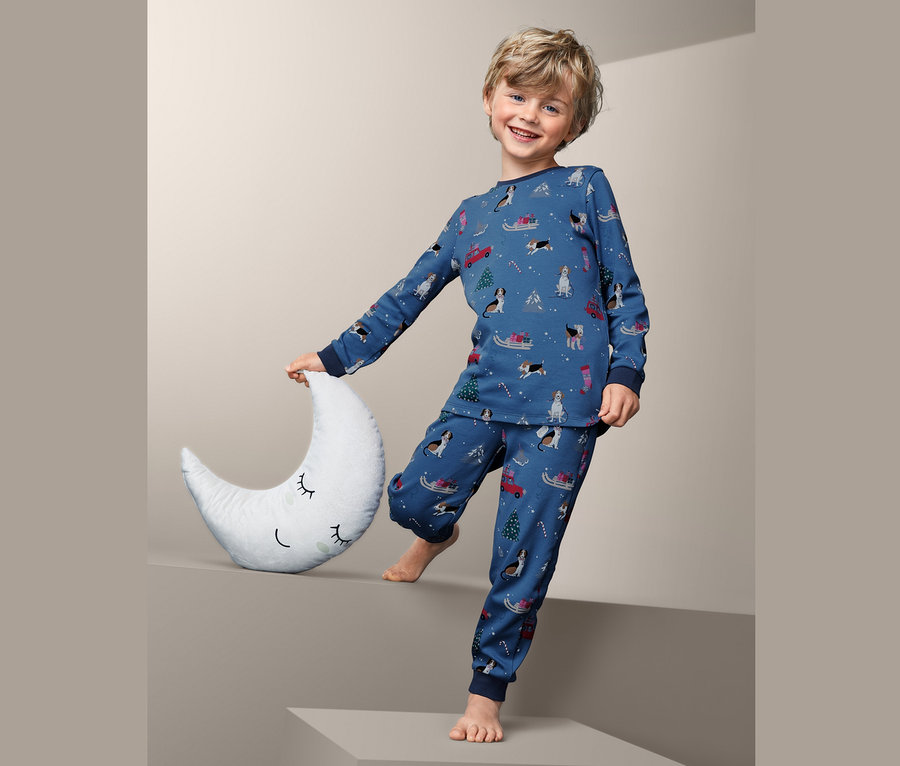 Chlapec drží měsíční polštář a má na sobě pyžamo z interlokové pleteniny s potiskem.