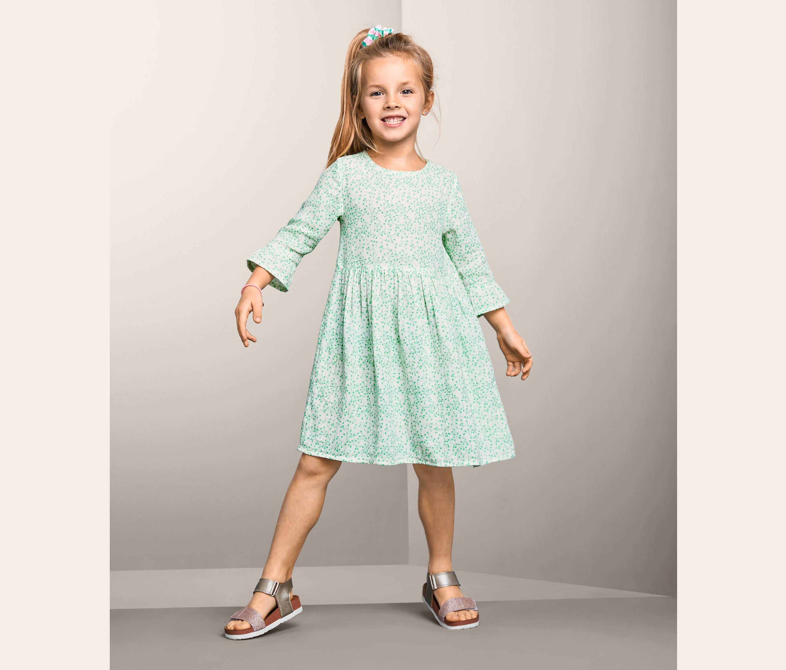 Usmívající se dívka pózuje v bavlněných tkaných šatech.