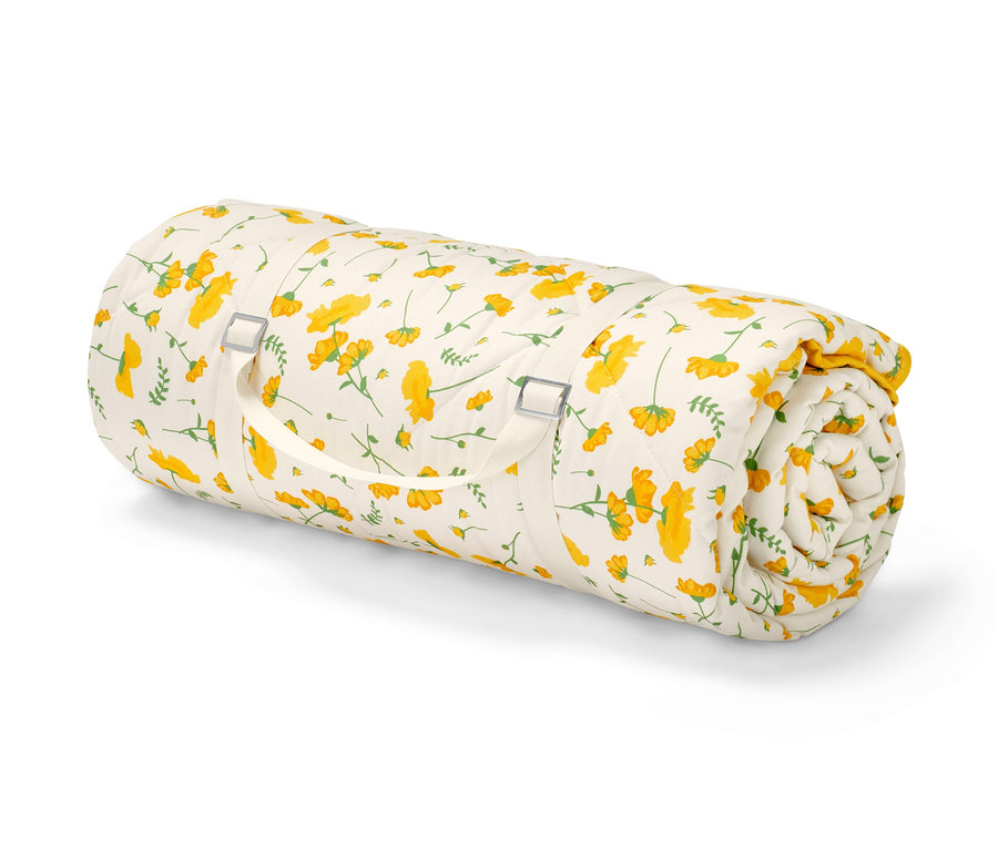 Srolovaná vatovaná pikniková deka s květinovým vzorem.