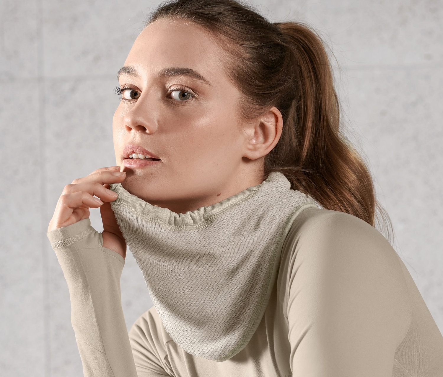 Žena nosí světle hnědý multifunkční termo šátek a top s dlouhým rukávem.