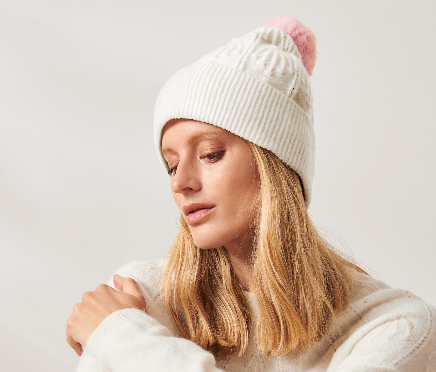 Žena sedí a má na sobě pletenou čepici s bambulí.