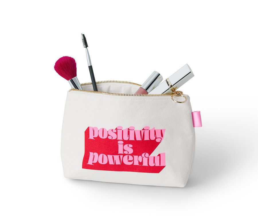 Kosmetická taštička s nápisem "positivity is powerful" a kosmetickými štětci.