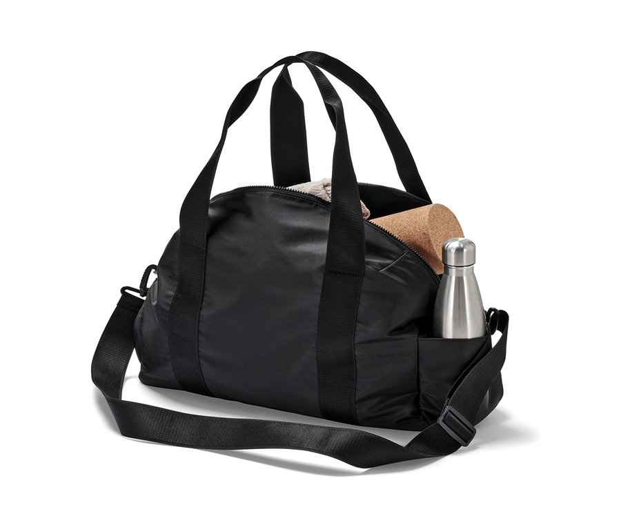 Černá sportovní taška se stříbrnou lahví na vodu a korkovou kostkou.