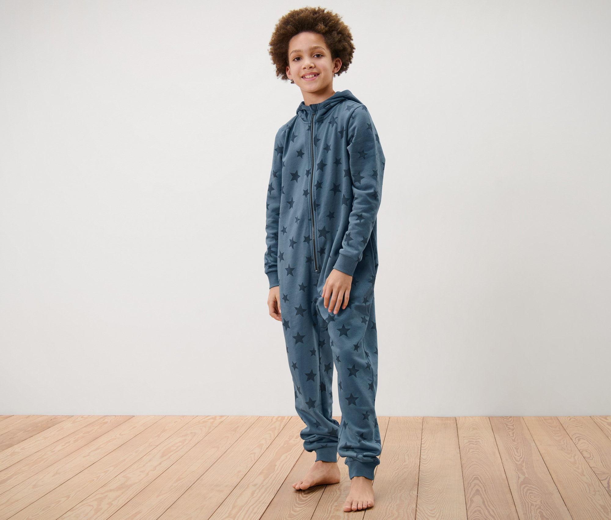 Chlapec stojí a má na sobě dětský pohodlný overal s hvězdami.