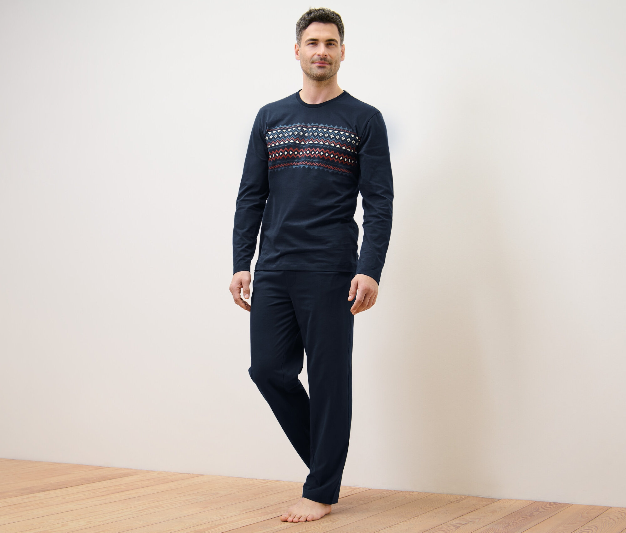 Muž stojí a má na sobě tmavě modré pyžamo s norským vzorem.