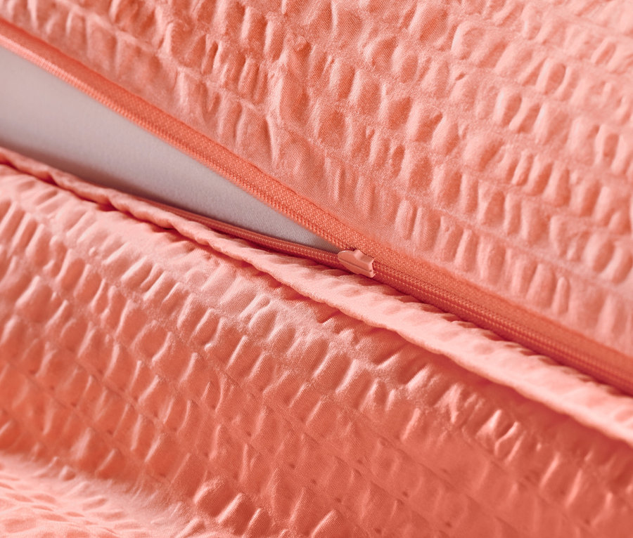 Detailní záběr na korálové krepové povlečení se zipem.