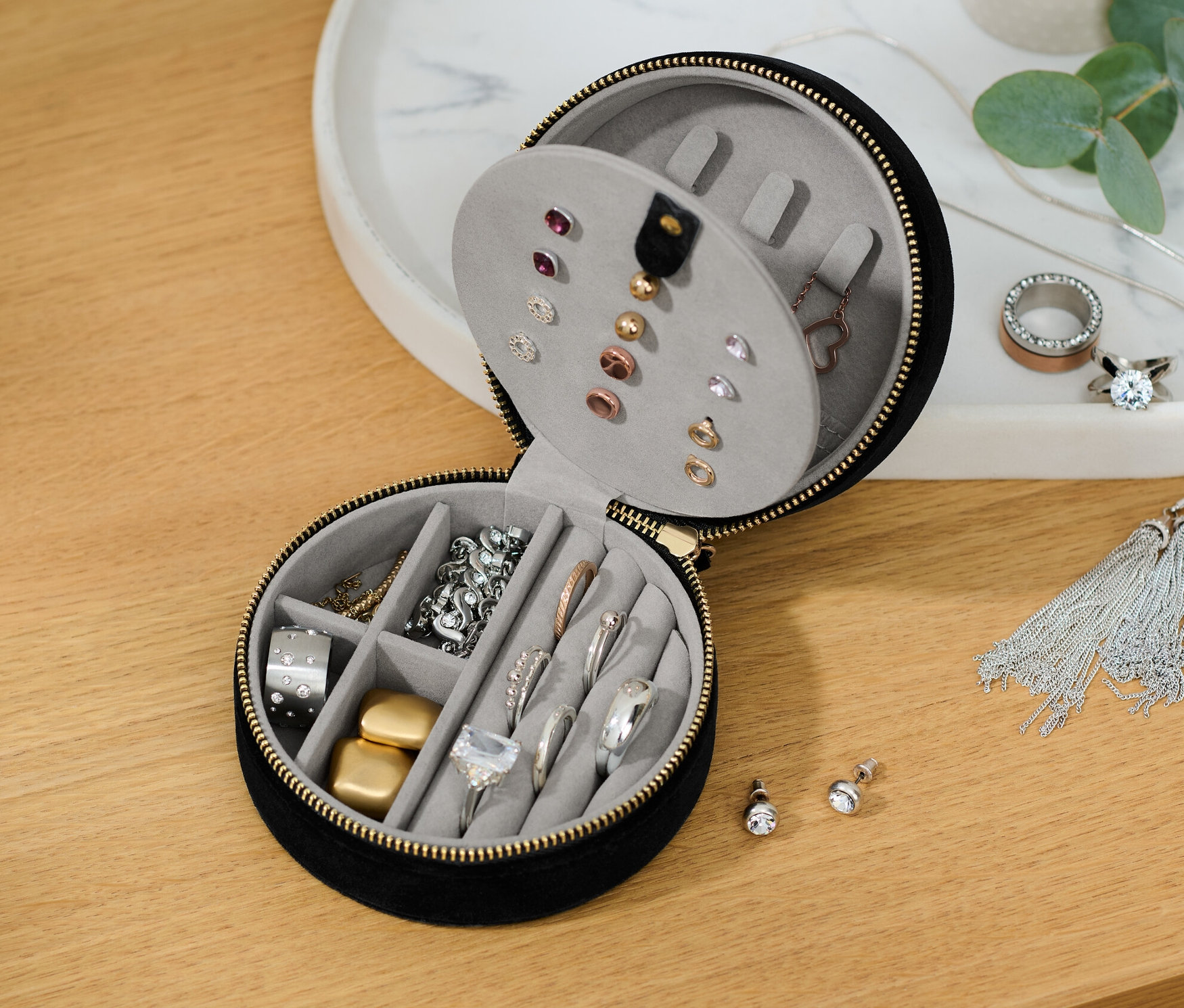Částečně otevřená malá šperkovnice s různými šperky uvnitř.