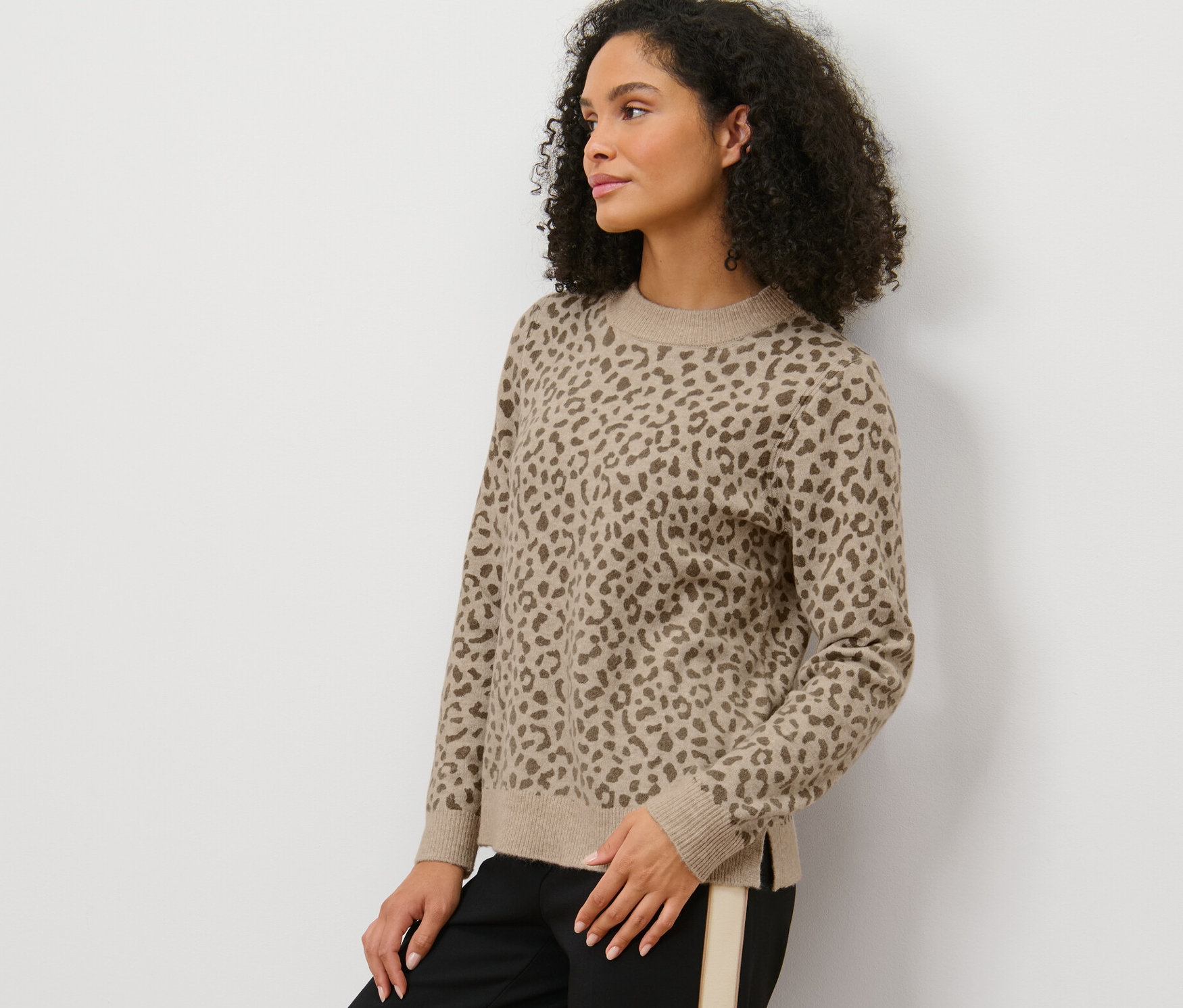 Žena pózuje v pleteném svetru s potiskem.