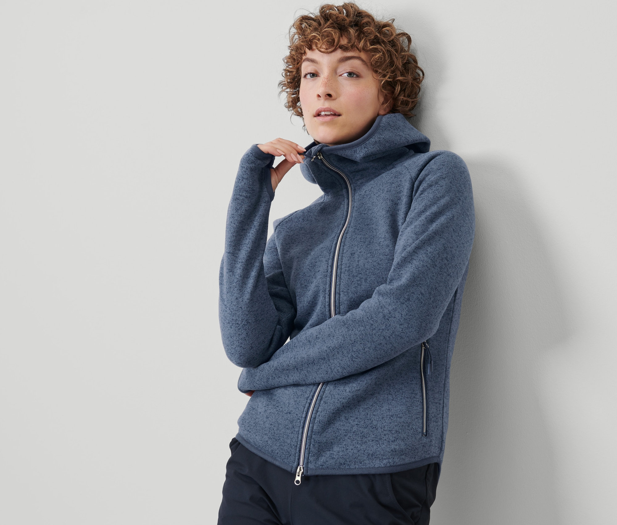 Žena si zapíná bundu z pleteného fleecu.