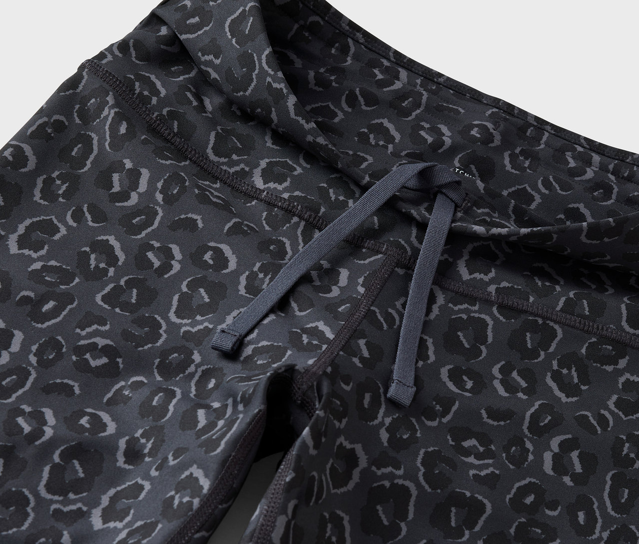 Detail dámských legín se stahovací šňůrkou v pase a zvířecím vzorem.