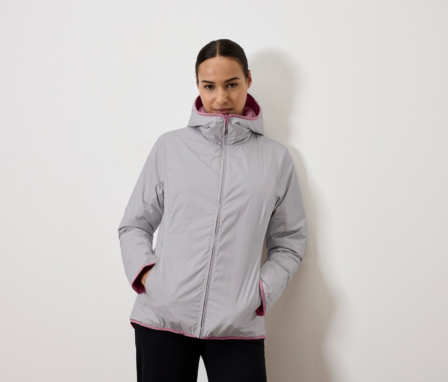 Žena má na sobě šedou bundu s kapucí s fialovou podšívkou.