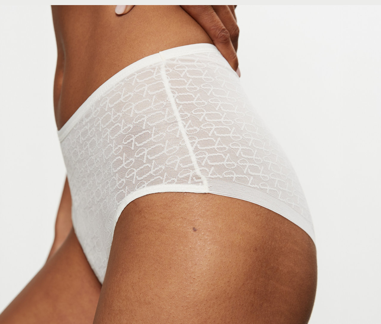 Detail osoby v krémově bílých, vysokých, průsvitných maxi kalhotkách Triumph Signature Sheer Maxi EX se vzorem.