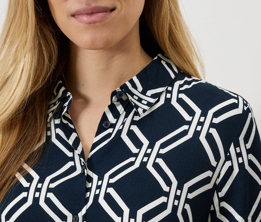 Detail dámské košile s geometrickým vzorem.