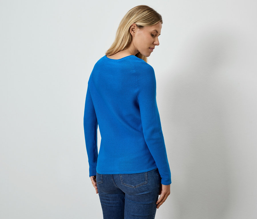 Žena zobrazená zezadu má na sobě modrý top a džíny.