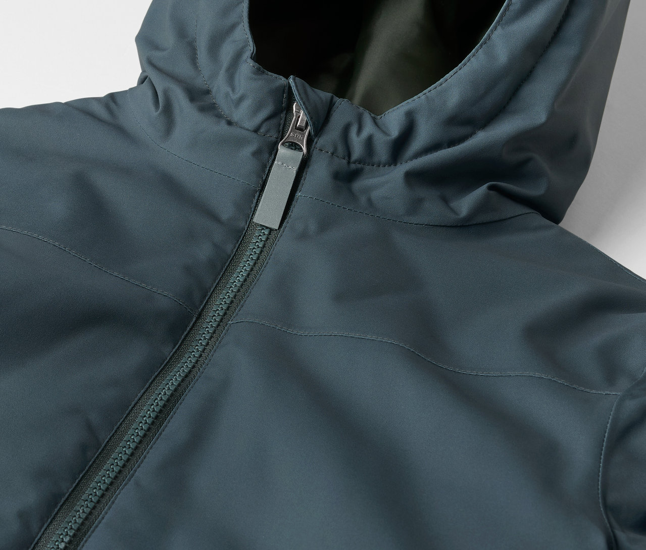 Detail dětské zimní bundy s kapucí a zipem.