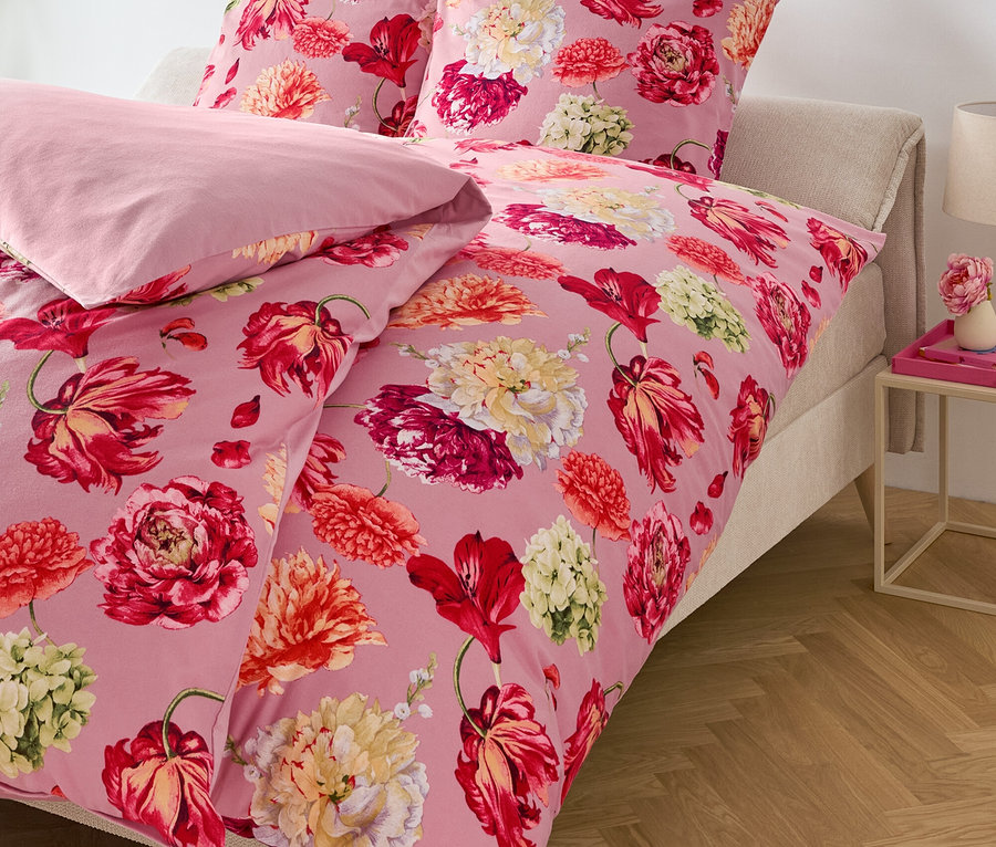Růžové ložní prádlo s květinovým vzorem na posteli.