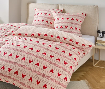 Postel s povlečením s motivem Mickey Mouse a dvěma polštáři s podobným vzorem.