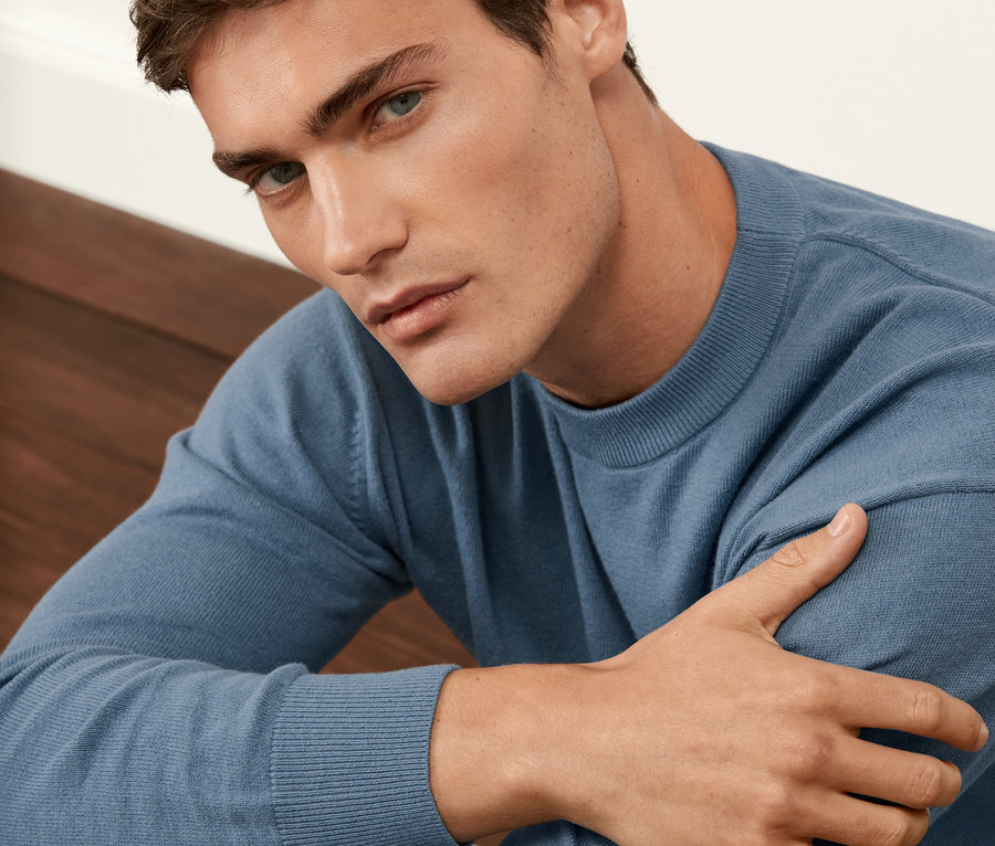 Muž má na sobě modrý svetr.