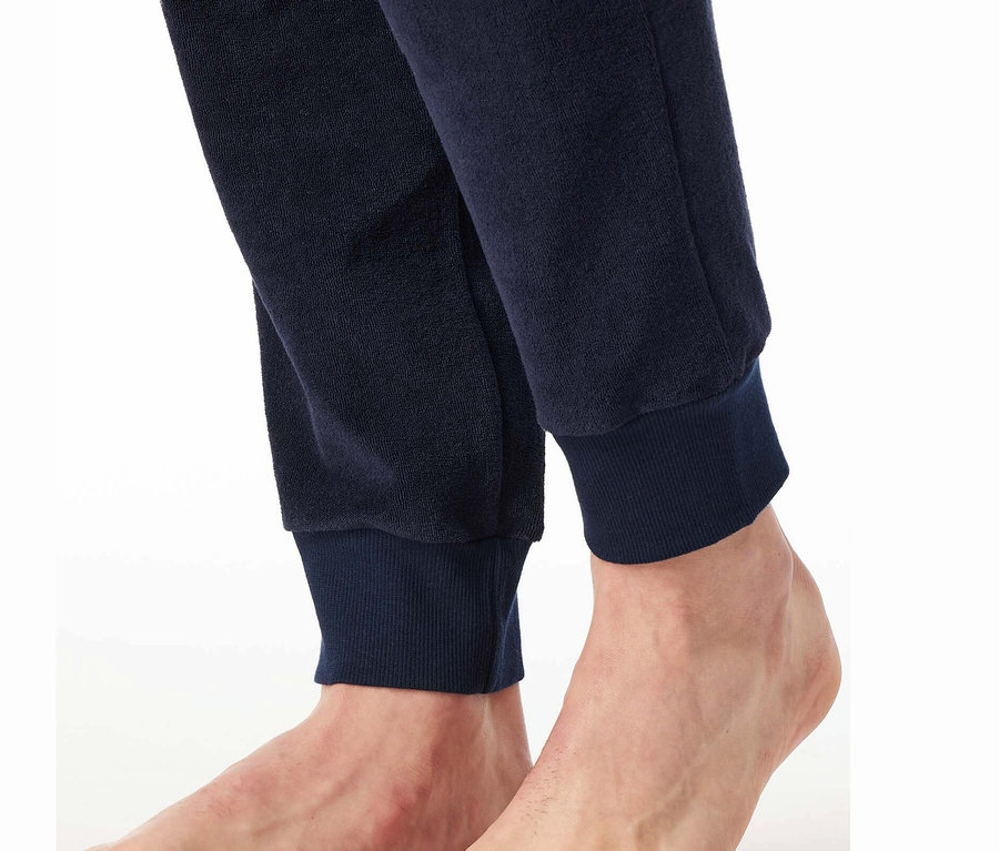 Detail nohou a spodku tmavě modrých tepláků.