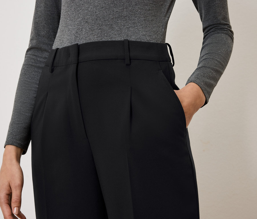 Žena má ruku v kapse černých kalhot.