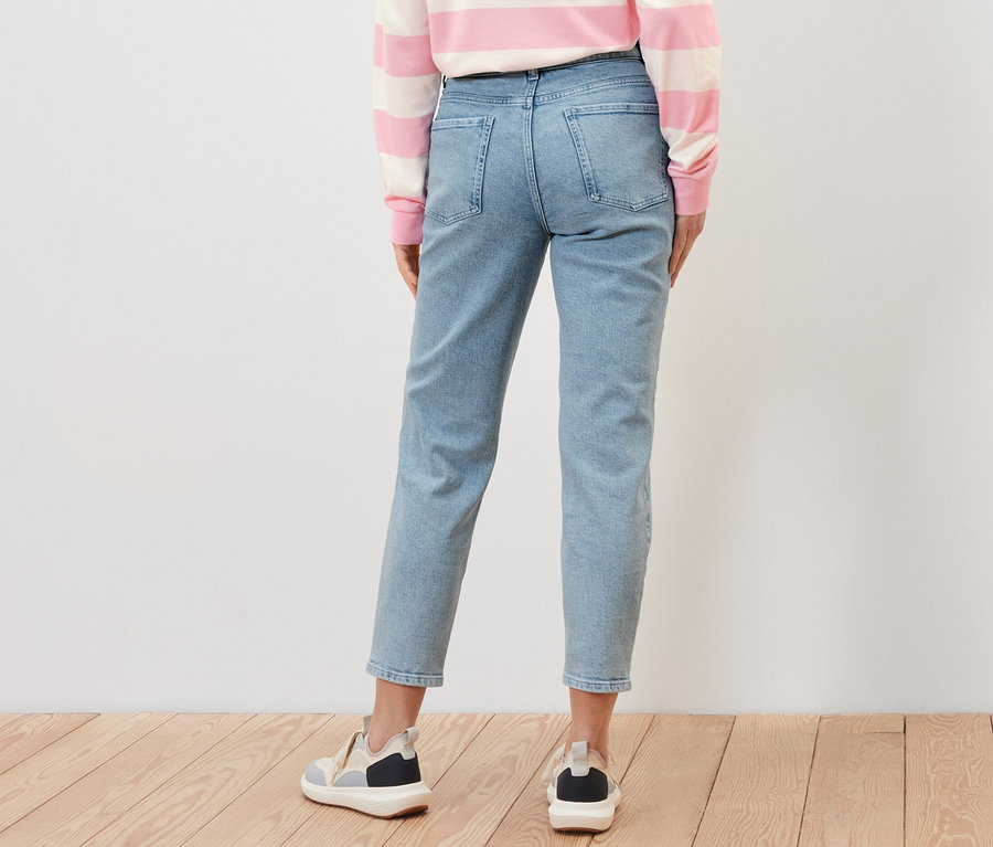 Žena zezadu v džínách Mom – Fit »Nyla«, pruhovaném topu a teniskách.