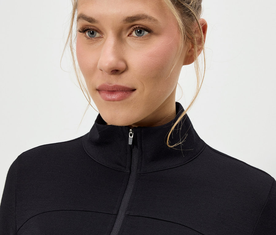 Detail ženy s blond vlasy v černé bundě na zip.