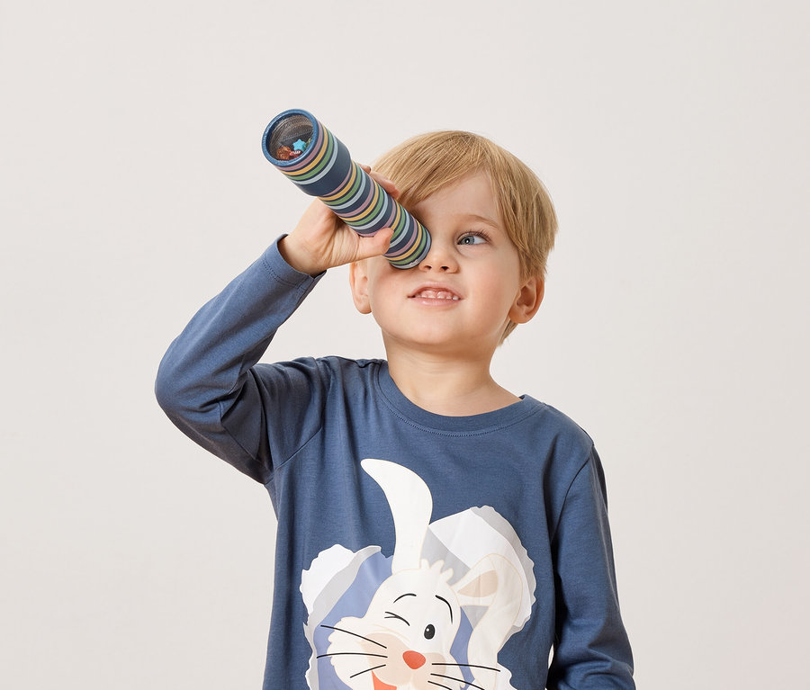 Blonďatý chlapec se dívá skrz kaleidoskop.