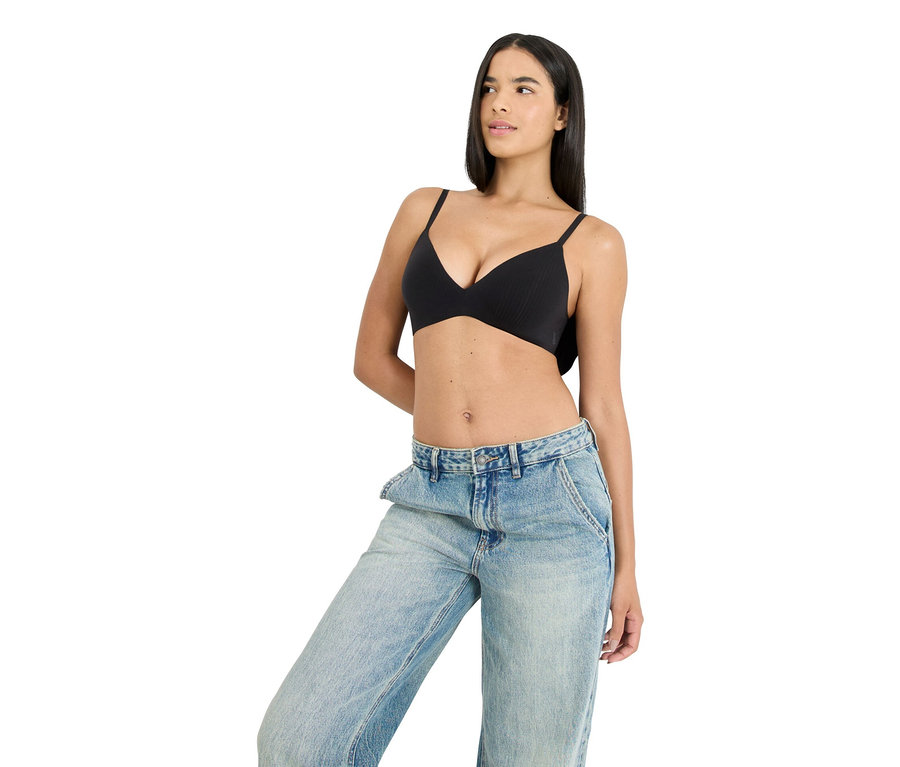 Žena má na sobě černou podprsenku a modré džíny.