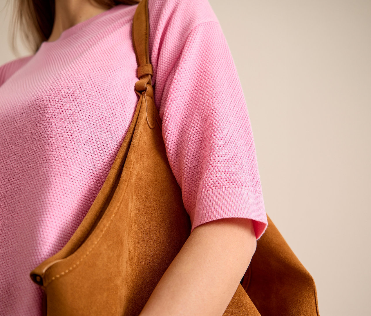 Žena má na sobě růžový svetr s krátkým rukávem CECIL a hnědou tašku přes rameno.