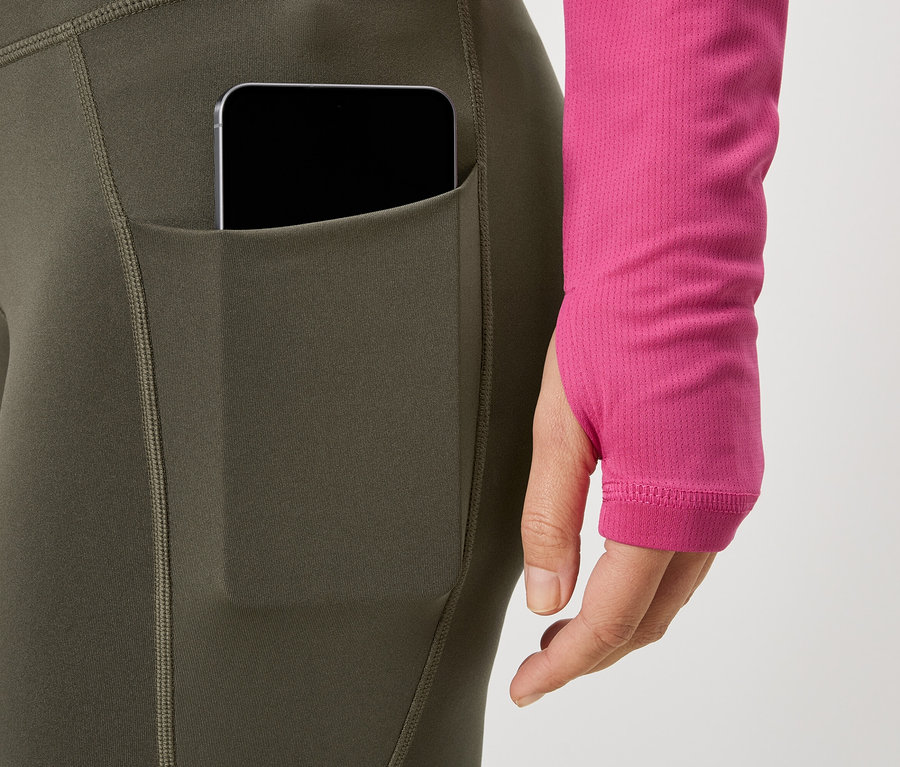 Žena má na sobě legíny s kapsou na telefon a růžový top.
