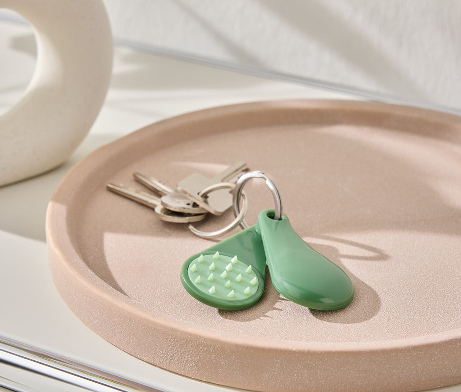 Klíče a zelená klíčenka leží na růžovém talíři.