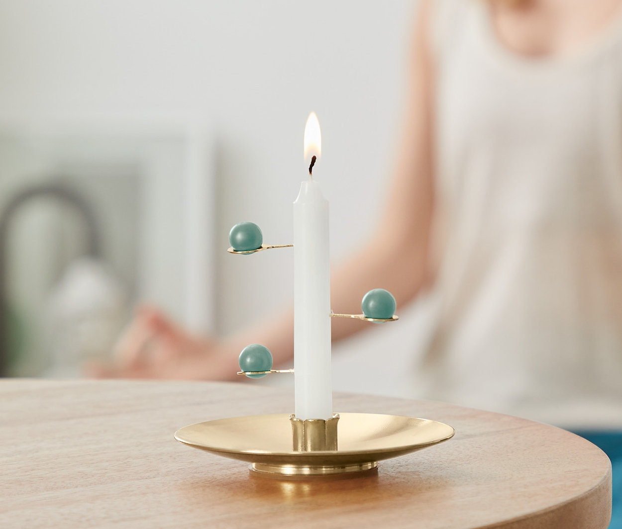 Hořící Meditační svíčka na stole, v pozadí žena v meditační pozici.